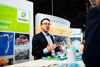 Dr. Christian Ruff, Project Manager Nuclear Technology at Bilfinger SE, in an engaged discussion with a participant at the sponsor’s booth during binding.energy