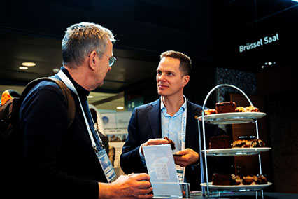 Dr. John Kettler, moderator of binding.energy and nuclear expert, shares a relaxed and engaged conversation with a participant during a coffee break — illustrating his commitment to connecting people across the nuclear industry