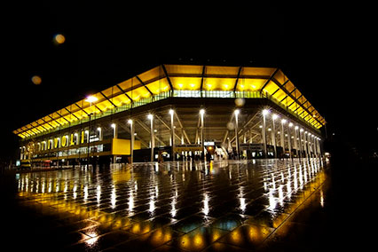 Tivoli Aachen entrance at night, showcasing illuminated yellow roof and modern glass facade, reflecting binding.energy’s blend of architectural elegance and dynamic conference environment