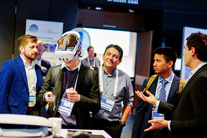Participant explores virtual reality nuclear training developed with industry by TU Dresden at the binding.energy exhibition while others engage in expert discussions on fusion and fission