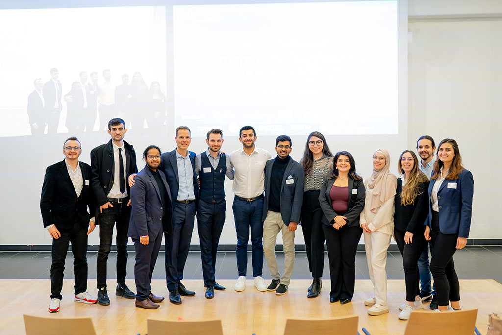 Group of early-career participants, including students and PhD researchers, gathered informally in front of the stage during a networking break at binding.energy, the international conference on nuclear technologies.